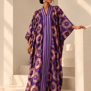 Model wearing the purple Simi Silk Rayon Bubu on a minimalist staircase, showing the African tie-dye motifs and striped Aso Oke front trim.