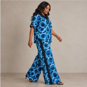 Side view of the blue Zuri Polo Adire set, showing an Aso Oke trouser stripe, extra-wide legs and a buttoned sleeve tab.